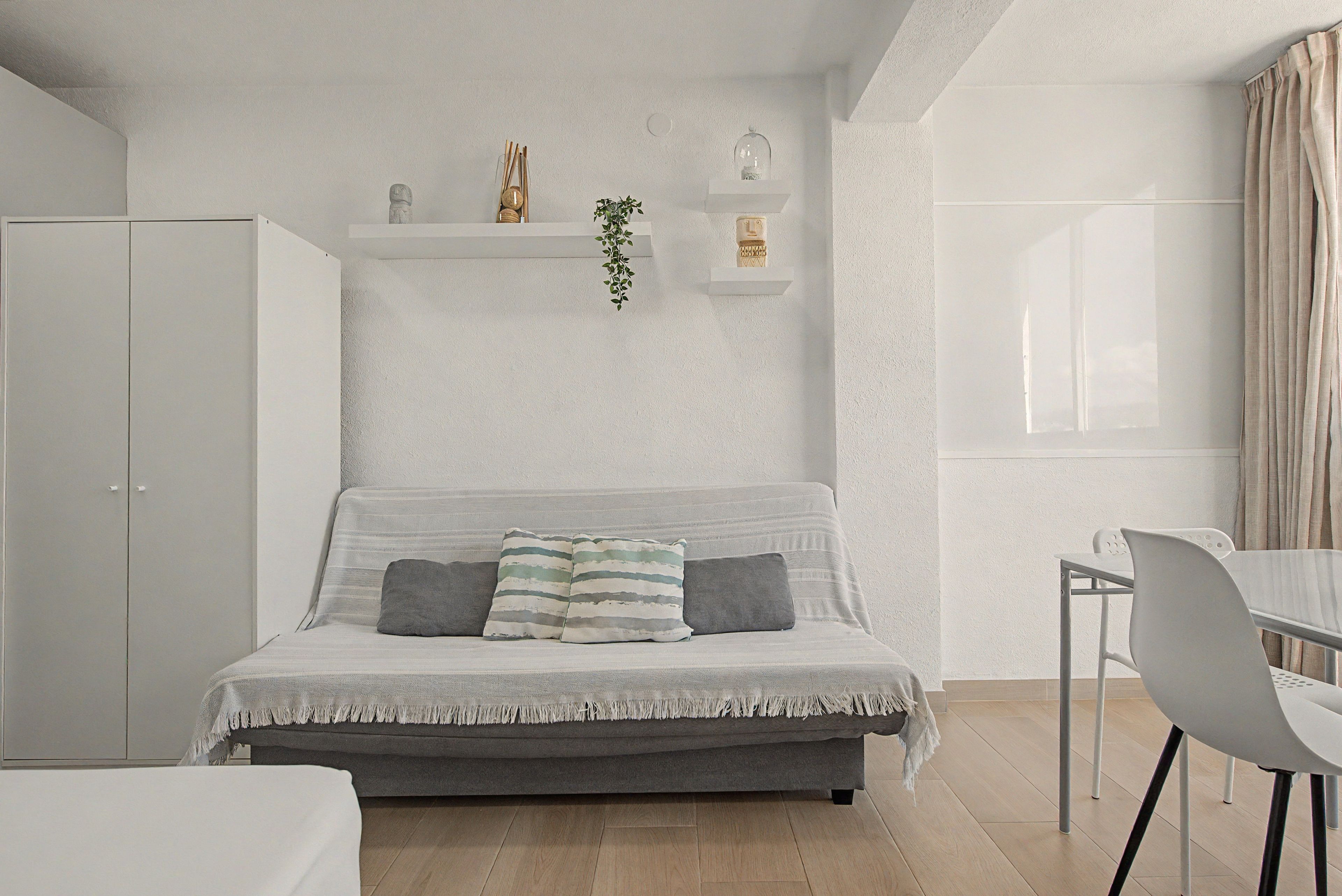 Een moderne slaapkamer met een grijze bank, een klein tafeltje en een witte inbouwkast.
