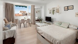 Une chambre d’hôtel moderne dotée d’un grand lit, d’une télévision, d’un coin repas et d’un balcon avec des rideaux.