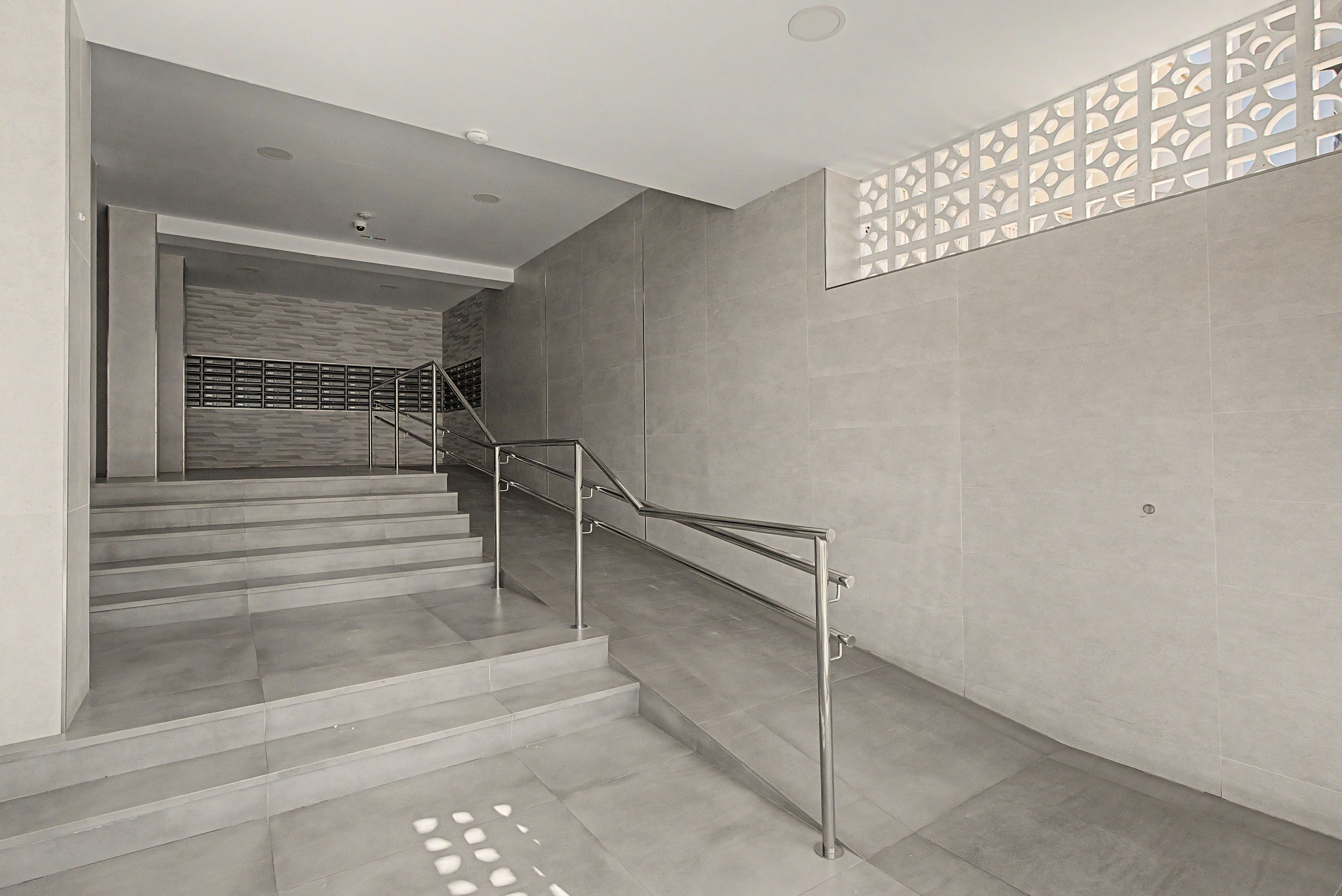 Eine moderne Treppe mit Metallgeländern und einem dekorativen Wandmuster.