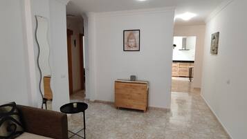 Ein Flur mit einer Couch, einem kleinen Tisch, einem Holzschrank und einer Buddha-Statue an der Wand.