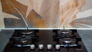 A kitchen with a gas stove and a wall with abstract leaf patterns. - Apartment 'La Casa Del Cuore' with Mountain View, Wi-Fi and Air Conditioning (Lascari)