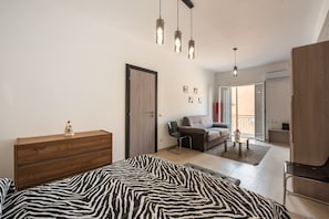 Une chambre à coucher moderne avec une couvre-lit à motifs zébrés, une commode en bois et un bureau avec une chaise.