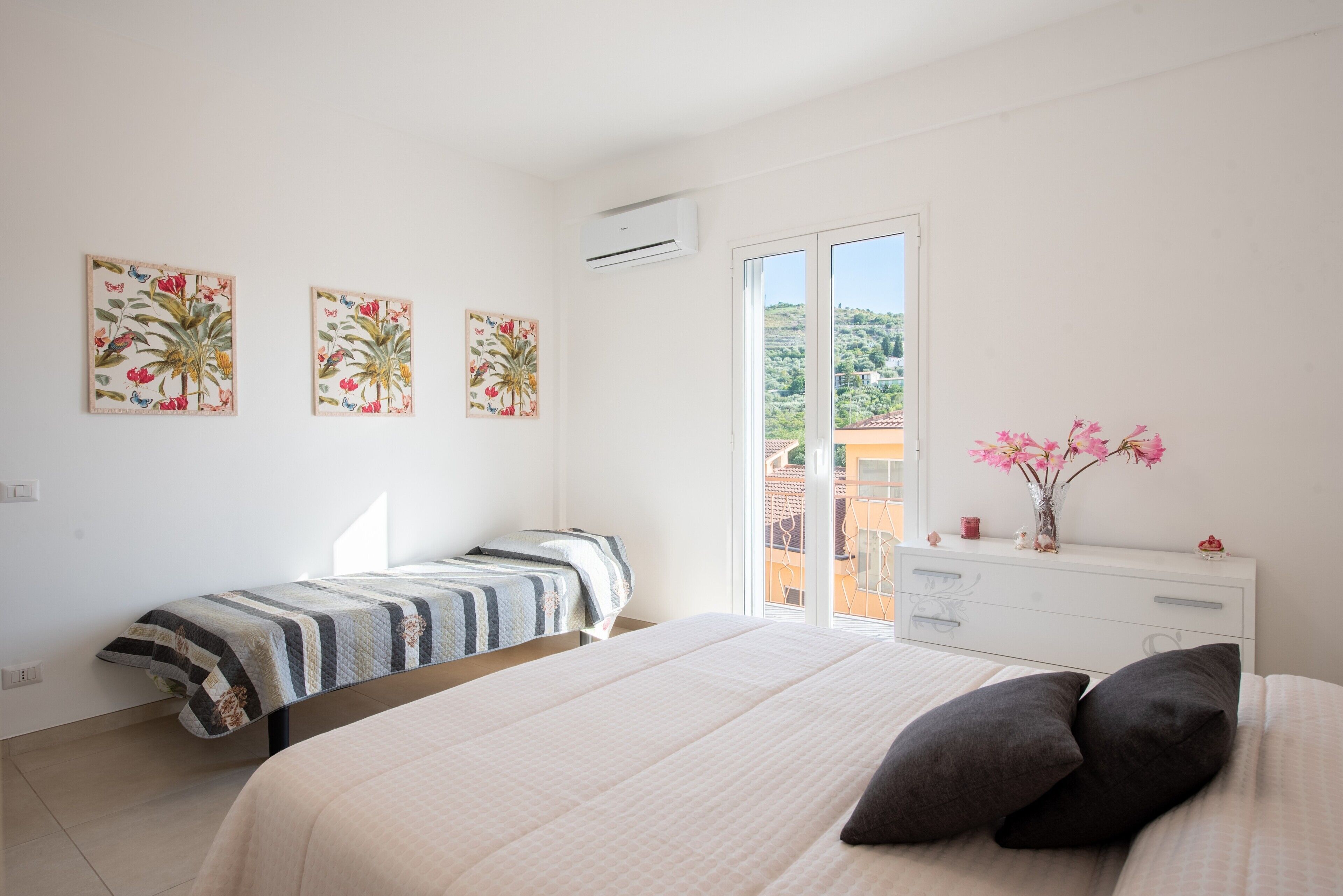 A bedroom with a bed, a nightstand, a dresser, and a window with a view.