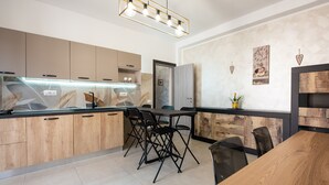 A modern kitchen with wooden cabinets, a black countertop, and a dining area with a wooden table and chairs. - Apartment 'La Casa Del Cuore' with Mountain View, Wi-Fi and Air Conditioning (Lascari)