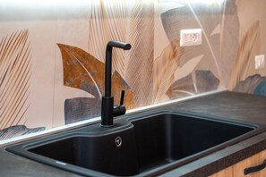 Un évier de cuisine doté d’un robinet moderne, d’un plan de travail et d’un pare-éclaboussures orné de motifs de feuilles.