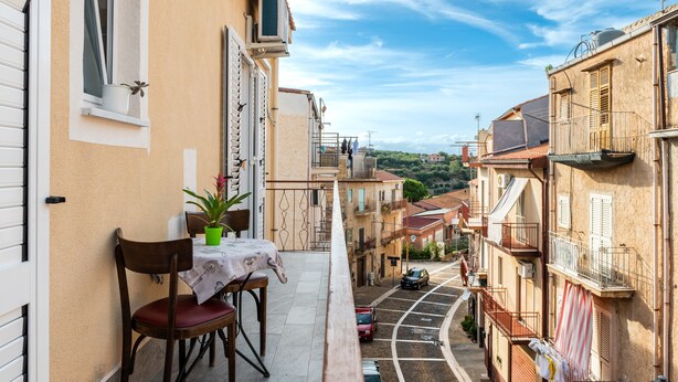 A narrow street with buildings on either side, a table with chairs, and a potted plant. - Apartment 'La Casa Del Cuore' with Mountain View, Wi-Fi and Air Conditioning (Lascari)