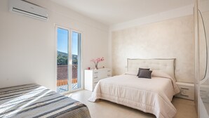 A bedroom with a bed, a bedside table, a dresser, and a sliding glass door to a balcony. - Apartment 'La Casa Del Cuore' with Mountain View, Wi-Fi and Air Conditioning (Lascari)