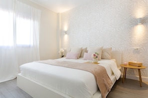 A bedroom with a large bed, a bedside table, a wall-mounted light, and a window with curtains. - Vacation Apartment 'Martimar Candelaria' with Sea View, Shared Pool and Wi-Fi (Candelaria)