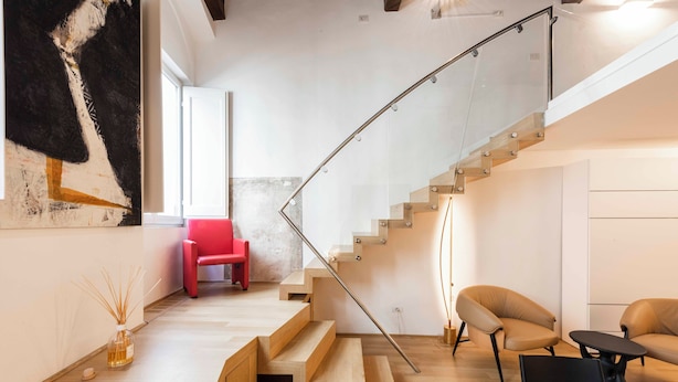 Un interior moderno con una escalera, suelo de madera y mobiliario minimalista.