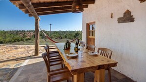 A wooden table with chairs, a hammock, and a view of the landscape. - Holiday Home 'Casa Moinho Da Eira' with Mountain View, Wi-Fi and Air Conditioning (Loulé)