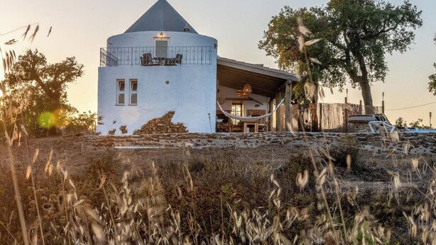 A white building with a conical roof, a balcony with chairs, and a wooden structure with a hammock. - Holiday Home 'Casa Moinho Da Eira' with Mountain View, Wi-Fi and Air Conditioning (Loulé)
