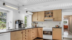 Una cocina moderna con armarios de madera, un lavamanos de acero inoxidable y un horno empotrado.