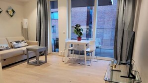 A modern living room with a sofa, a small table, a glass coffee table, and a view of the outside through large windows. - Oslo Center, Norway, your second home. (Oslo)