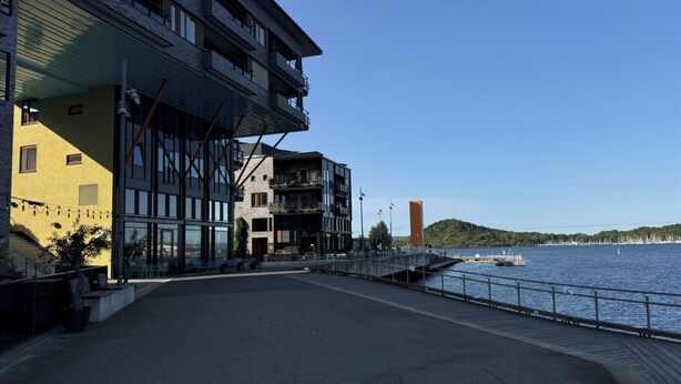 A waterfront building with multiple floors, large windows, and a covered walkway. - Oslo Center, Norway, your second home. (Oslo)
