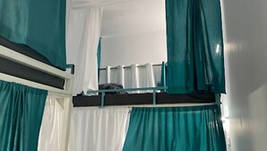 A bunk bed with teal curtains and a white curtain.