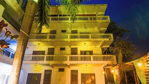 A multi-story building with balconies, outdoor seating, and a white fence.
