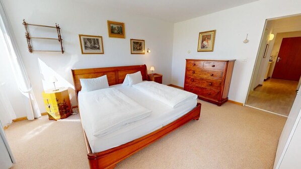 A bedroom with a wooden bed, a wooden dresser, and a mirror. There are framed pictures on the wall. - Well-kept holiday apartament house in a prime location in St. (St. Moritz)