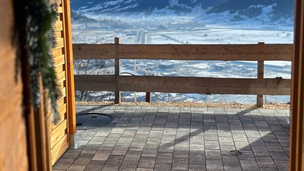 A wooden deck with a view of snow-covered mountains.