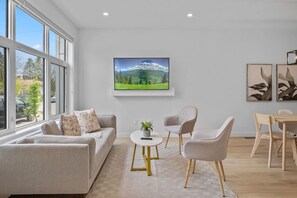 Una sala de estar moderna con un sofá, dos sillones, una mesa de centro y un cuadro en la pared.