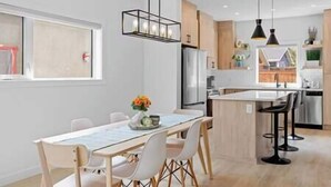 A modern kitchen with a central island, white cabinetry, and pendant lighting.