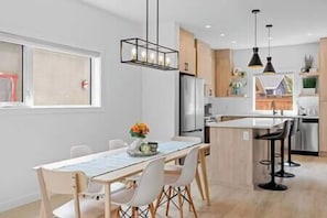 Uma cozinha moderna com ilha central, armários brancos e iluminação pendente.