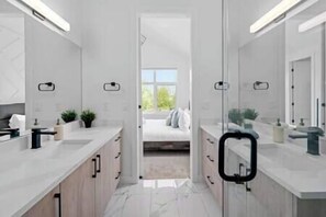 Un baño moderno con un espejo grande, un lavamanos y una zona de ducha.