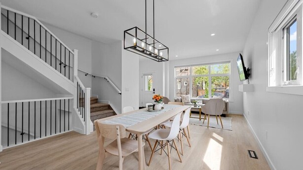 A modern interior with a staircase, dining area, and a TV mounted on the wall.