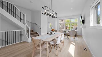 Un intérieur moderne avec un escalier, un coin repas et un téléviseur fixé au mur.