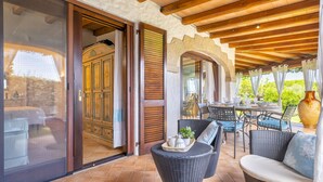An outdoor patio with wicker furniture, a dining table, and a large vase.