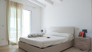 Un dormitorio con cama, mesita de noche, lámpara y ventana con cortinas.