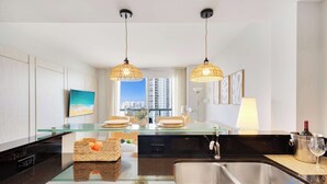 A modern kitchen with a glass island, stainless steel sink, and pendant lighting. - 1BR Apartment with beautiful view (Sunny Isles Beach)