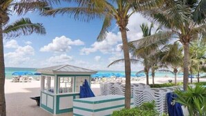 A beachside kiosk with a small shelter, surrounded by palm trees and beach chairs. - 1BR Apartment with beautiful view (Sunny Isles Beach)