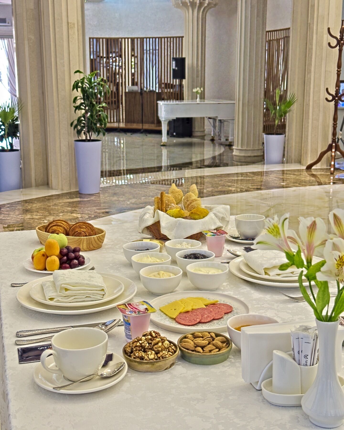 A breakfast buffet with various food items and a piano in the background.