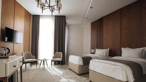 Ein Hotelzimmer mit zwei Betten, einem Schreibtisch, einem Stuhl und einem Fernseher.
