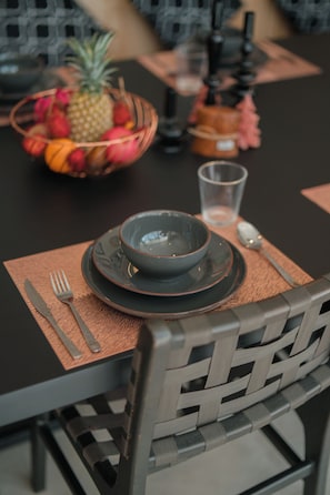 A dining table set with a bowl, plates, cutlery, and a fruit basket. - Villa Hani Canggu (Canggu)