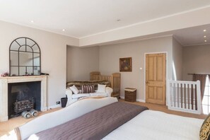 Une chambre à coucher avec un grand lit, une cheminée, une porte en bois et une balustrade blanche.