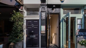A building entrance with a black door, a sign above it, and a signboard to the right advertising brunch.