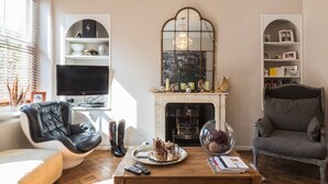 A living room with a fireplace, a television, a black leather chair, a grey armchair, and a coffee table with a tray.