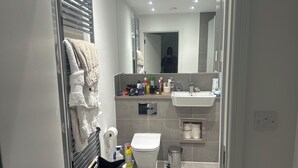 Een moderne badkamer met toilet, wastafel en diverse toiletartikelen.