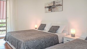 Une chambre à coucher avec un lit, deux tables de chevet, une commode, une lampe et un tableau au mur.