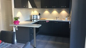 Eine moderne Küche mit dunklen Schränken, einer weißen Arbeitsplatte und einem Edelstahlspülbecken.
