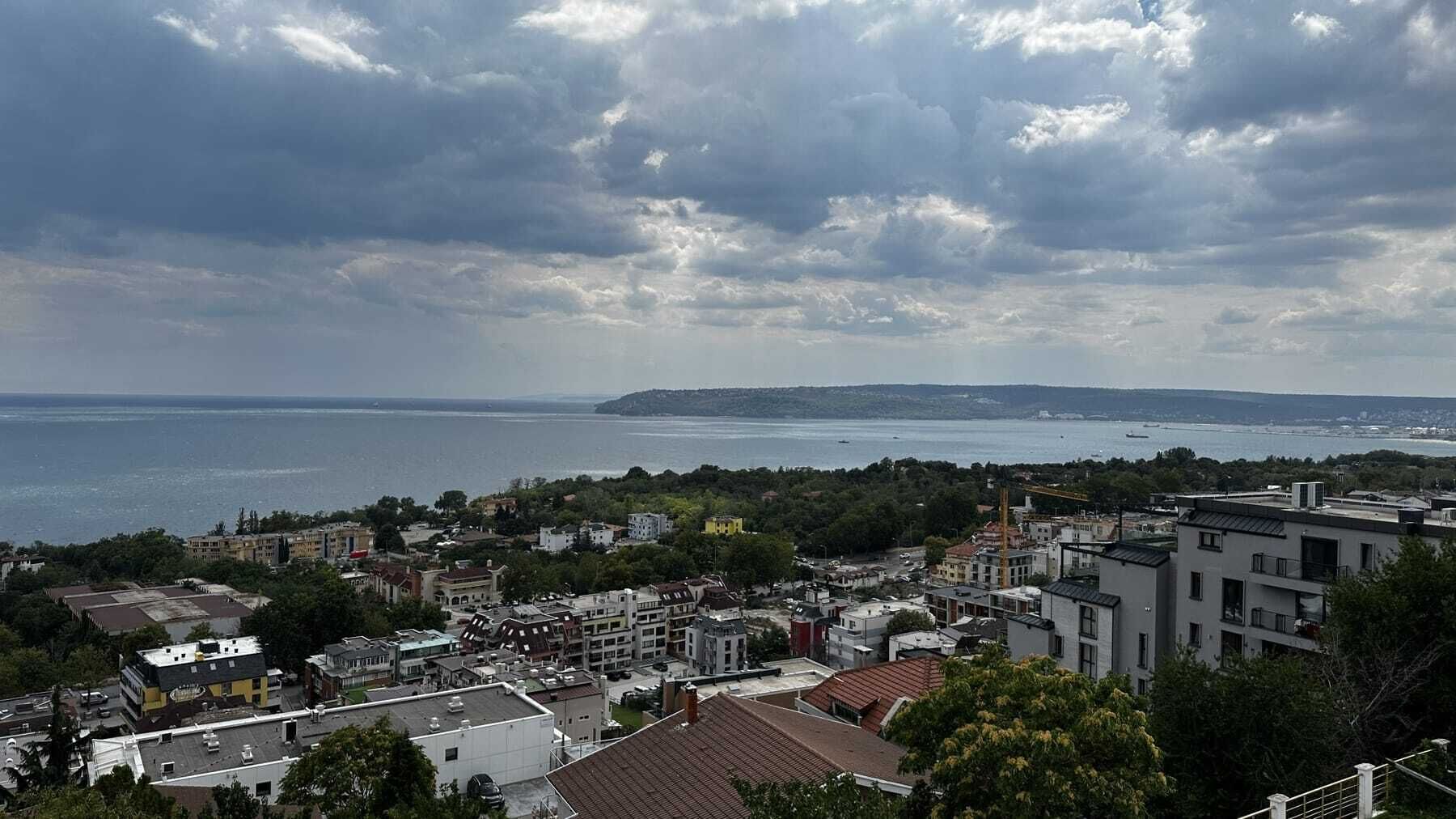 Uma cidade costeira com edifícios, vista para o mar e céu nublado.