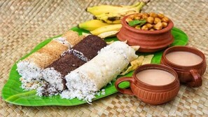 A plate with various food items, including a banana, chickpeas, and two types of rice cakes, served on a green leaf. - The Violet Thekkady (Peermade)