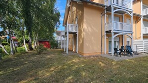 Monikerroksinen rakennus, jossa on parvekkeita ja pieni ulkona sijaitseva oleskelualue.