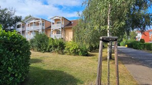 Asuinalue, jossa on kaksikerroksinen talo, jossa on parvekkeet ja hyvin hoidettu nurmikko.