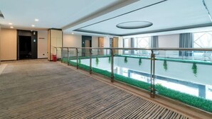 A spacious indoor area with a glass barrier, a green artificial garden, and a modern ceiling design. - GreenTree Inn Express Hotel (Yangzhou Slender West Hunan Branch) (Yangzhou)