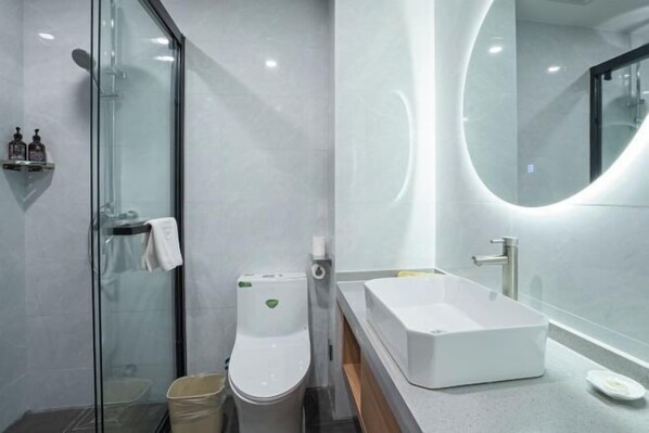A modern bathroom with a glass-enclosed shower, a white toilet, a rectangular sink, and a round mirror. - GreenTree Inn Express Hotel (Yangzhou Slender West Hunan Branch) (Yangzhou)