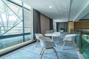 A modern hotel room with a large window, a round table with chairs, and a small kitchenette area. - GreenTree Inn Express Hotel (Yangzhou Slender West Hunan Branch) (Yangzhou)