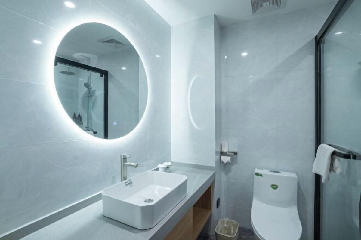 A modern bathroom with a large mirror, a rectangular sink, and a toilet.