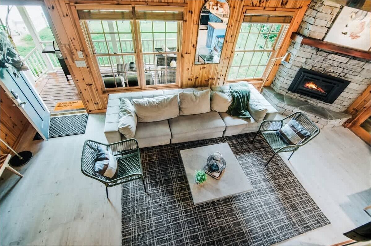 A cozy room with a wooden sofa, two chairs, a coffee table, and a fireplace.